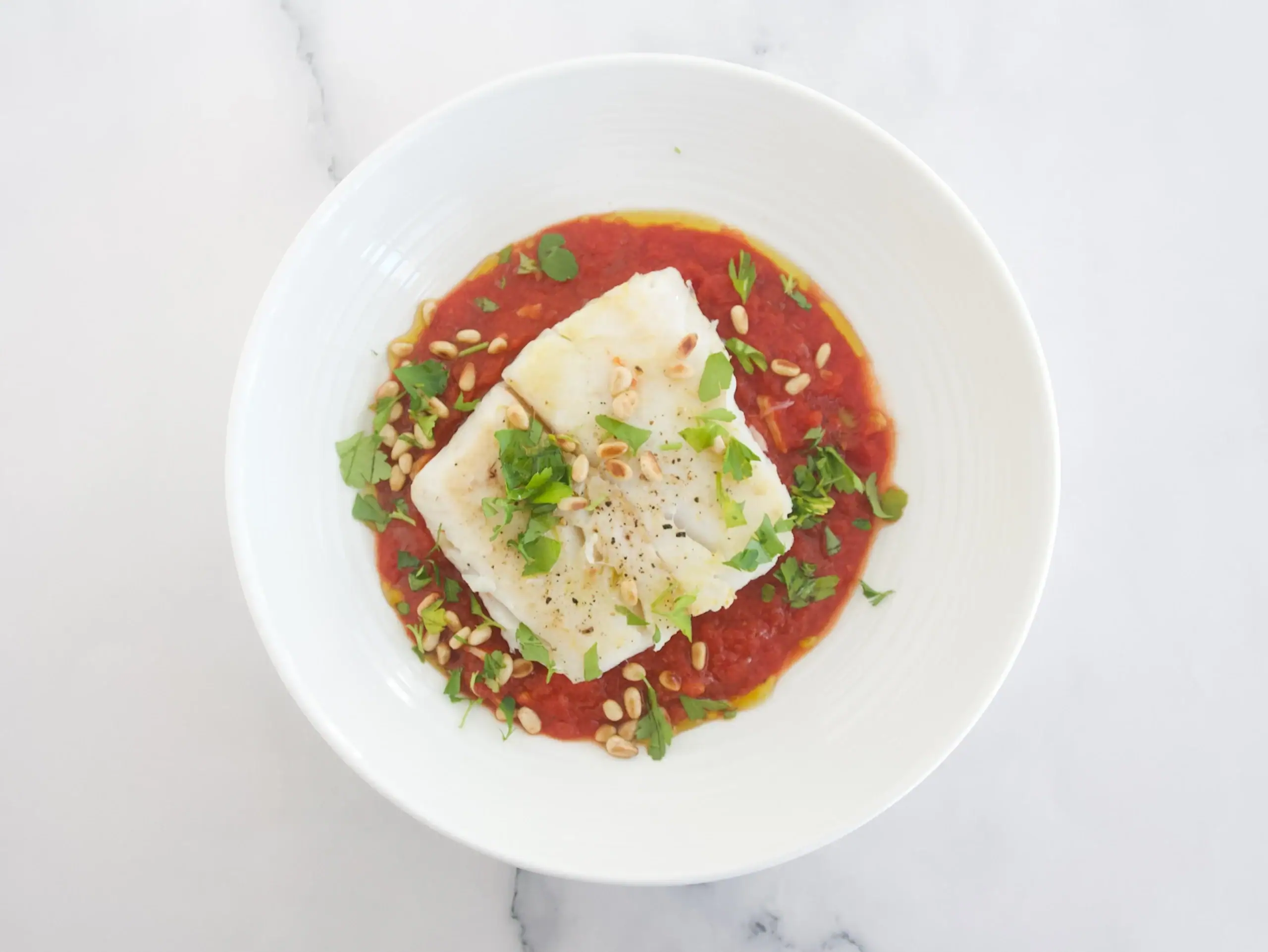 Merluza con salsa de tomate y piñones