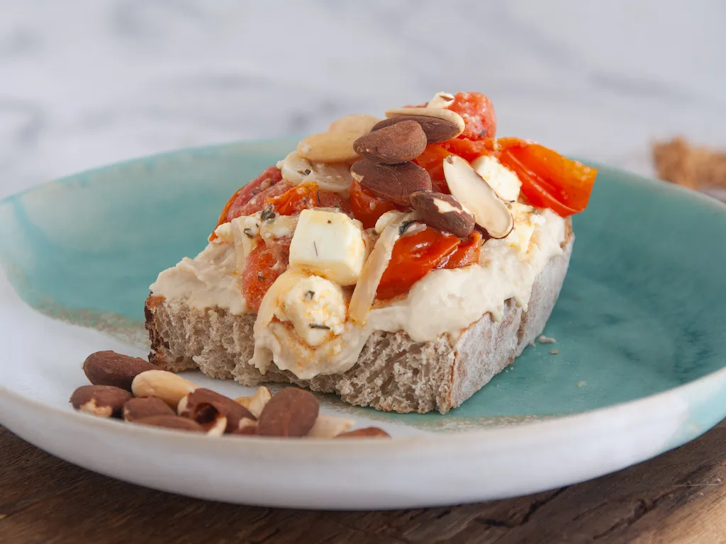 Tostada de hummus con tomates asados con feta